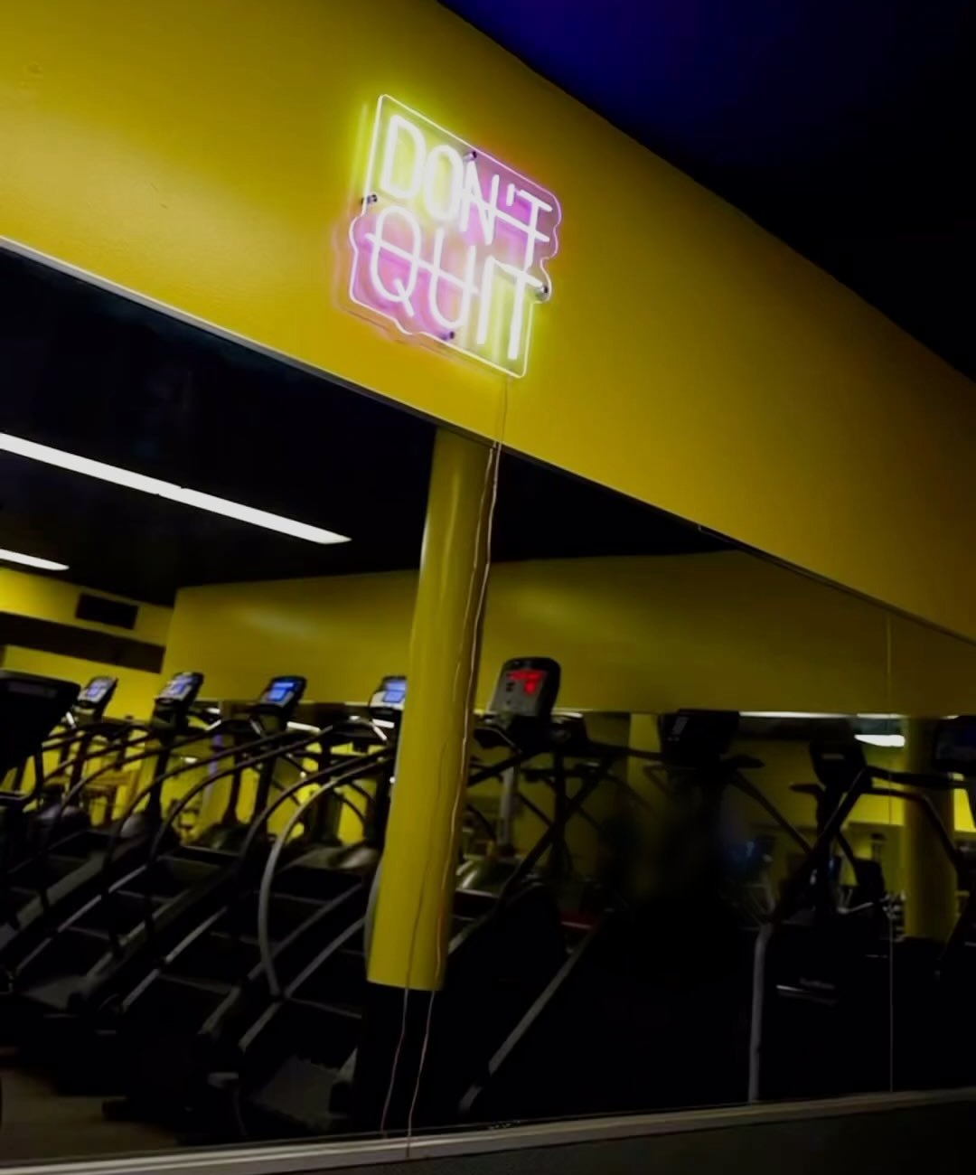 Yellow beam with a pink and white “Don’t Quit” neon sign above the cardio row at Fit Nation Norwalk