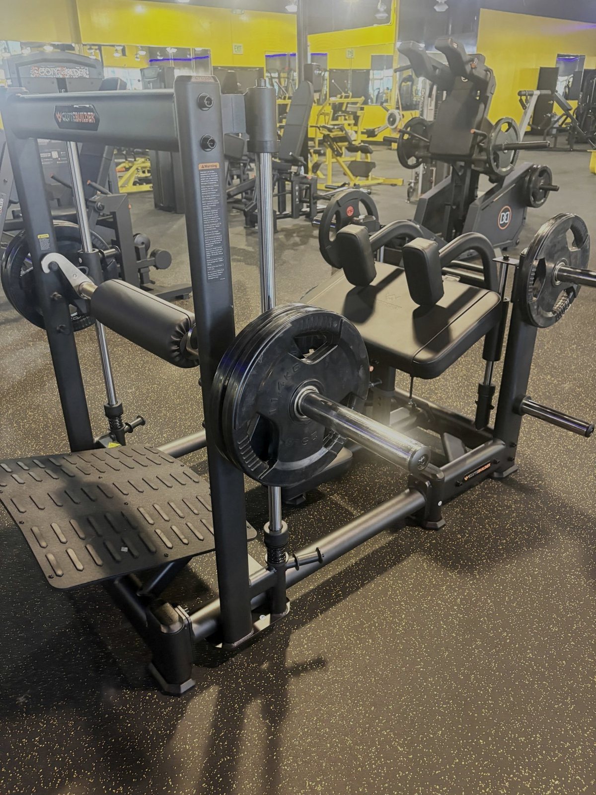 Plate-loaded machines in front of the yellow walls at Fit Nation Ontario